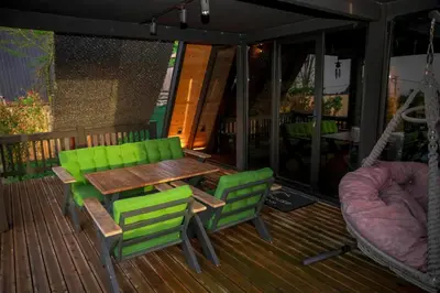 a wooden table and two green chairs on a deck at Hill House Bungalov in Sapanca