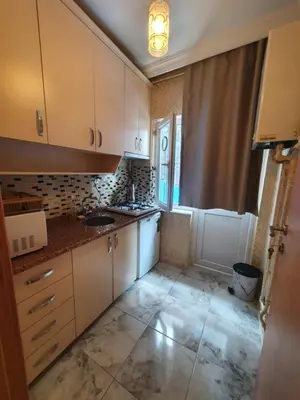 a small kitchen with white cabinets and a window at Efe Apart Hotel in Istanbul