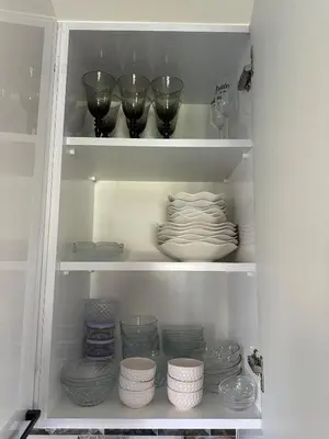 a cupboard filled with plates and bowls and wine glasses at Lilyum garden house&organization in Söylemiş