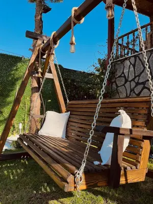 a wooden swing with two pillows on it at Lilyum garden house&organization in Söylemiş