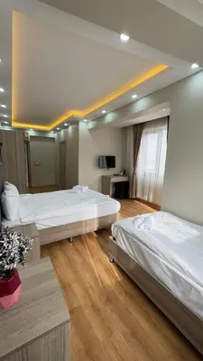 two beds in a large room with wooden floors at Lions Boutique Hotel in Altınova