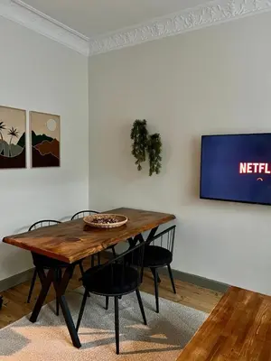 a dining room table with chairs and a television on a wall at Old Town Loft in Balat in Istanbul