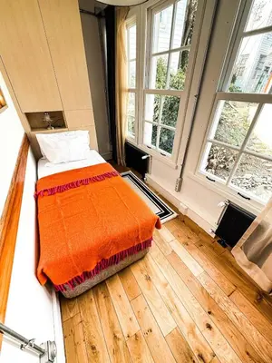 a bed with an orange blanket in a room with windows at Rent the Entire Bosphorus House in Istanbul