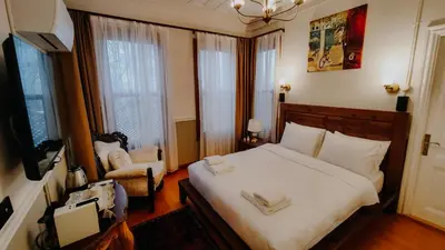 a bedroom with a bed and a chair and windows at Leila Mansion Hotel in Tekirdag
