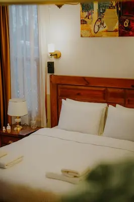 a bed with a wooden headboard and white pillows at Leila Mansion Hotel in Tekirdag