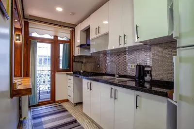 a kitchen with white cabinets and black counter tops at Mutlu flat in Istanbul