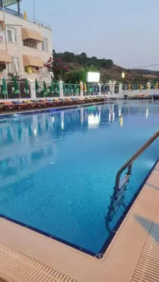 a large swimming pool with blue water in front of a building at Aydın Motel in Marmara