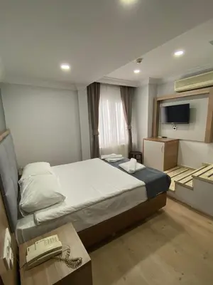 a bedroom with a bed and a desk and a television at Kafkas Hotel Istanbul in Istanbul
