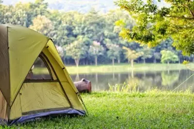 a yellow tent sitting in the grass next to a lake at NZR KAmP in Serdivan