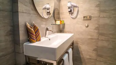 a bathroom with a white sink and two mirrors at Barbera Hotel in Istanbul