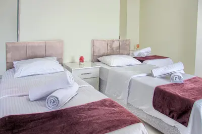 two beds in a room with white and purple sheets at Hotel yeniçiftlik in Yeniçiftlik