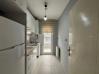 a small kitchen with white cabinets and a hallway at Zeus Suit Görükle in Nilüfer