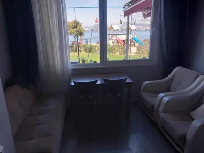a living room with a couch and a table and a window at Palmiye Pansiyon in Adalar