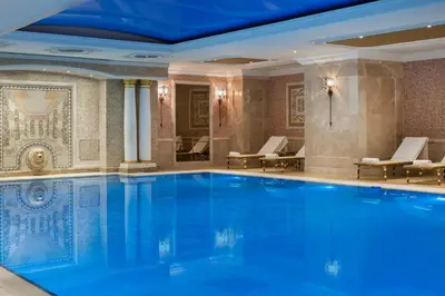 a large swimming pool in a hotel lobby with chairs at Elite World Istanbul Taksim in Istanbul