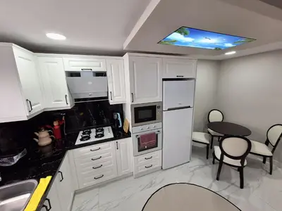 a kitchen with white cabinets and a sink and a table at Daly Resort 1 in Sapanca