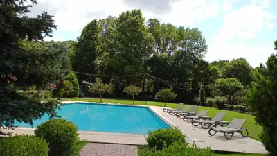a swimming pool with chaises and chairs around it at Villa Riva Garden in Polonezkoy