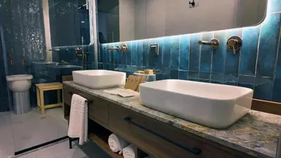 a bathroom with two sinks and a blue tiled wall at Yıldız Termal Otel in Çekirge İstasyonu