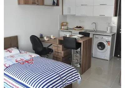 a bedroom with a bed and a desk and a kitchen at White Palace Apart in Istanbul