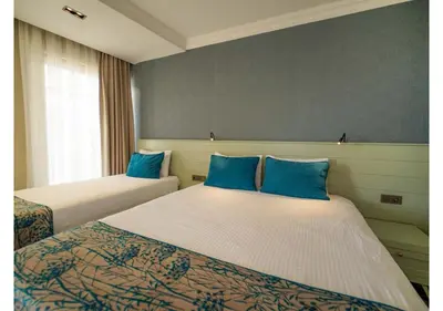 two beds in a hotel room with blue pillows at White Palace Apart in Istanbul