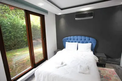 a bedroom with a bed with a blue headboard and a window at Sakarya Sapanca da Özel Havuzlu , Ailelere Özel Villalar in Sapanca
