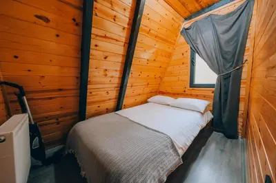 a bed in a wooden cabin with a window at Sakarya Sapanca Memnuniye de 3 Oda1 salon Özel Havuzlu-Jakuzili-Şömineli-Korunaklı 8 Kişilik Bungalov in Sapanca