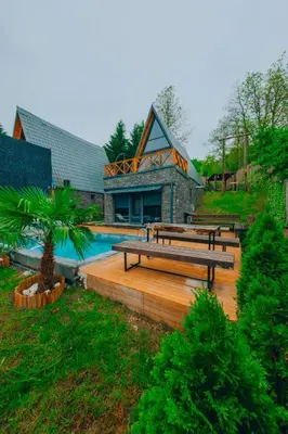 a group of benches sitting on a deck next to a house at Sakarya Sapanca Memnuniye de 3 Oda1 salon Özel Havuzlu-Jakuzili-Şömineli-Korunaklı 8 Kişilik Bungalov in Sapanca