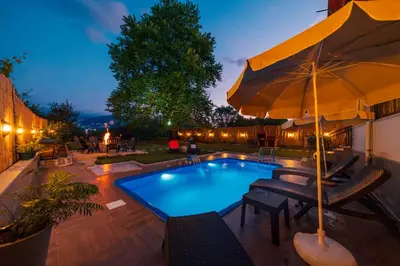 a swimming pool with chairs and an umbrella at Sepetçi Lakehouse Heated Pool in Kartepe