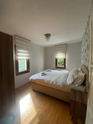 a bedroom with a bed with white sheets and two windows at Villa Luna Sapanca in Sakarya