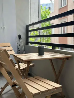 a wooden table and chairs on a balcony with a window at Modern 2Bedroom Apt in Şişli in Istanbul