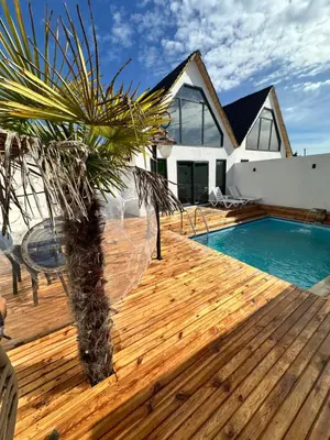 a wooden deck with a palm tree and a swimming pool at Bigados Otel & Bungalov in Silivri