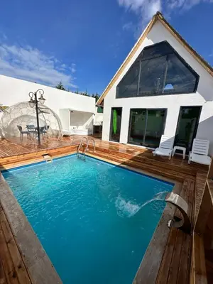 a swimming pool with a wooden deck and a house at Bigados Otel & Bungalov in Silivri