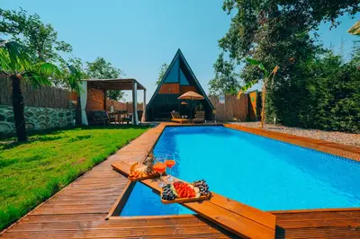 a swimming pool with a wooden deck next to a house at Maya Sapanca Bungalow in Sapanca