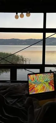 a person sitting on a bed with a laptop in front of a window at Flamingo aura in Sapanca