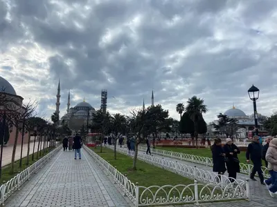 a group of people walking down a sidewalk in front of a mosque at Blue Star Apartments Old City Center in Istanbul