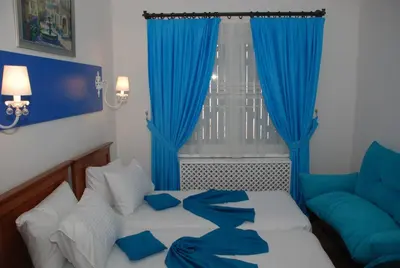a bedroom with a bed with blue curtains and a couch at Mavi Inci Park Otel in Erdek