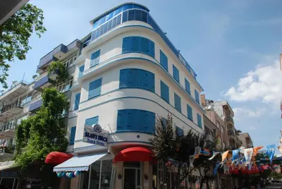 a tall white building with blue windows on a street at Mavi Inci Park Otel in Erdek