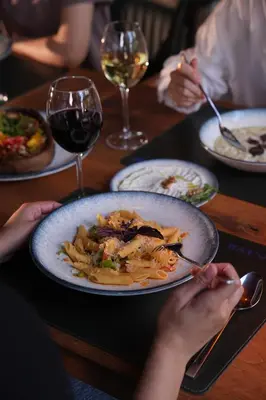 a table with a plate of food and glasses of wine at Navy Inn & Bungalows in Arnavutköy