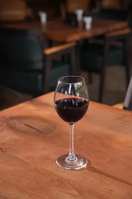 a glass of red wine sitting on a wooden table at Navy Inn & Bungalows in Arnavutköy