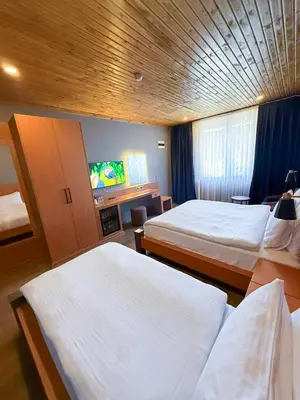 a hotel room with two beds and a flat screen tv at Navy Inn & Bungalows in Arnavutköy