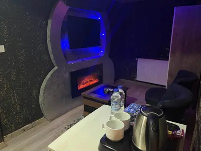a living room with a fireplace with a tv and a table at HEVİN Otel in Bursa