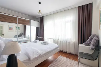 a bedroom with a white bed and a large mirror at Chic 2BR Gem on Moda Iconic Antiques Street in Istanbul