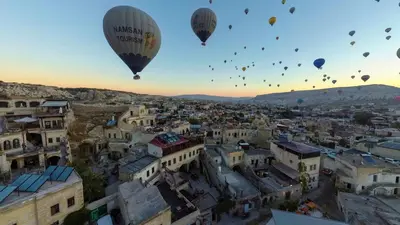 a group of hot air balloons flying over a city at Zenith Göreme in Istanbul