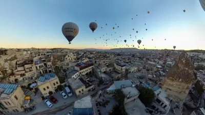 a group of hot air balloons flying over a city at Zenith Göreme in Istanbul