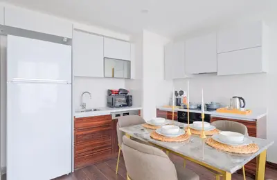 a kitchen with white cabinets and a table with chairs at Modern Furnished Apartments in Istanbul Basaksehir By Iradah Gayrimenkul in Basaksehir