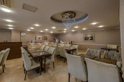 a restaurant with wooden tables and chairs and a chandelier at Mekanhan Hotel in Gebze