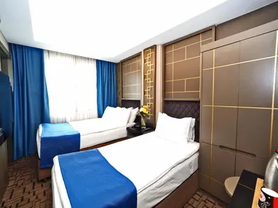 two beds in a hotel room with blue curtains at Grand Best Nobel Hotel İstanbul in Istanbul