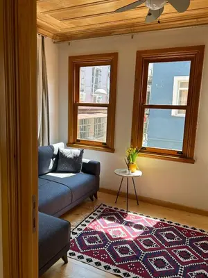 a living room with a couch and two windows at Balat Rose - Charming Wooden House with Terrace in Istanbul
