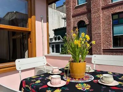 a table with cups and saucers and a vase with flowers at Balat Rose - Charming Wooden House with Terrace in Istanbul