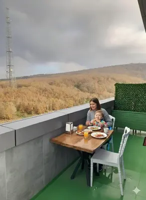 a woman and a baby sitting at a table with a view at Hmz Premium Konaklama Çekmeköy in Çekmeköy