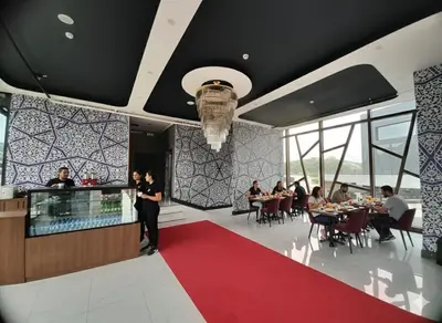 a man standing in a restaurant with people sitting at tables at Hmz Premium Konaklama Çekmeköy in Çekmeköy